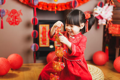 Close-up of girl holding red while standing outdoors