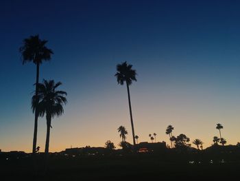 Silhouette palm trees against sky at sunset