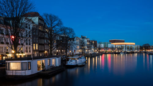 Boats moored on river by buildings in city