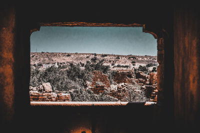 View of old ruin through window