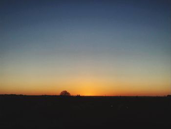 Scenic view of silhouette field against clear sky at sunset