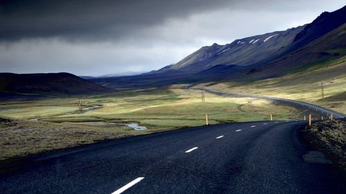 Road by mountains against sky