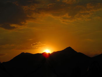 Scenic view of silhouette mountains against orange sky