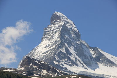 Low angle view of snowcapped mountains against clear blue sky