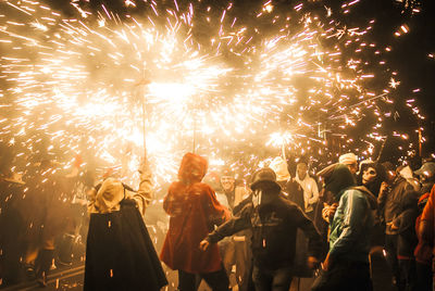 People burning sparklers on street at night