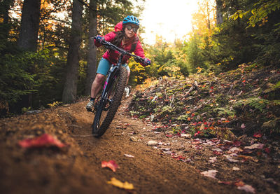 Man riding bicycle on road amidst trees in forest