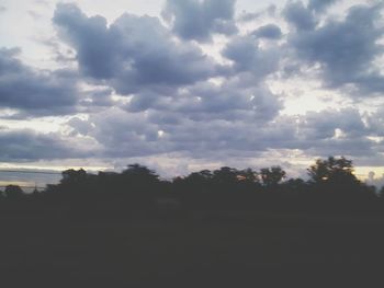 Silhouette trees against cloudy sky