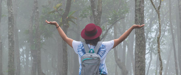 Rear view of woman standing by plants in forest