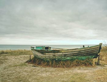 Abandoned boat on beach against sky