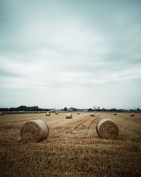 Hay bales on field against sky