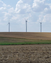 Wind turbines on field against sky