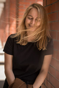 Portrait of young woman sitting against wall