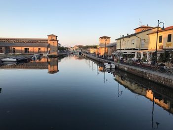 Reflection of buildings in city against clear sky