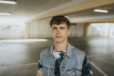 Portrait of young man in denim jacket at parking garage