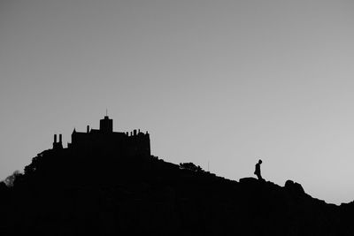 Low angle view of silhouette woman standing on rock against sky