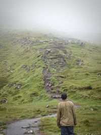 Rear view of man standing on landscape against sky