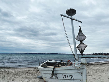 Fishing boat on beach against sky
