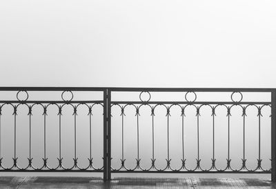 Metal railing by sea against clear sky