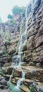 Low angle view of waterfall on rocks