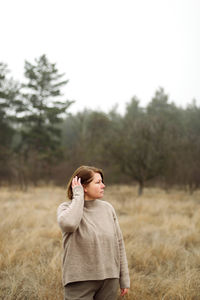 Woman standing by forest in foggy weather