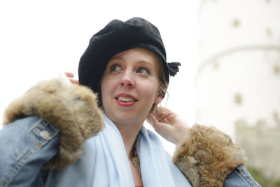 Smiling young woman wearing warm clothing while looking away against sky