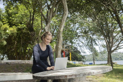 Young woman using a laptop at day time at a green park. mobile phone, technology,