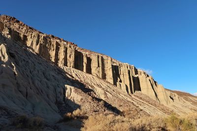 Low angle view of rocks against clear blue sky