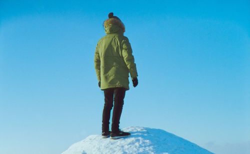 Rear view of man standing against clear blue sky