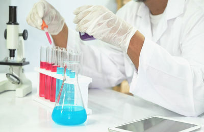 Midsection of scientist holding test tube at laboratory