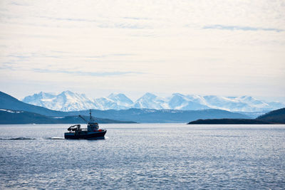 Sailboat sailing on sea against mountains