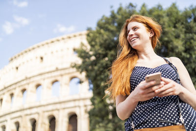 Optimistic ginger tourist browsing smartphone on sunny day