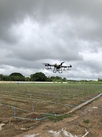 Airplane flying over field against sky