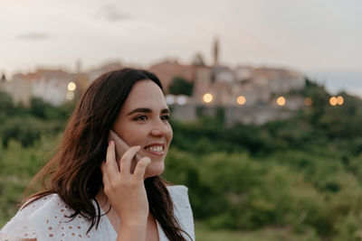 Candid portrait of happy young woman talking on the phone in city