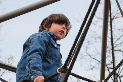 Low angle view of young boy standing on slide