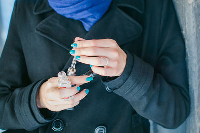 Midsection of woman holding electronic cigarette and dropper