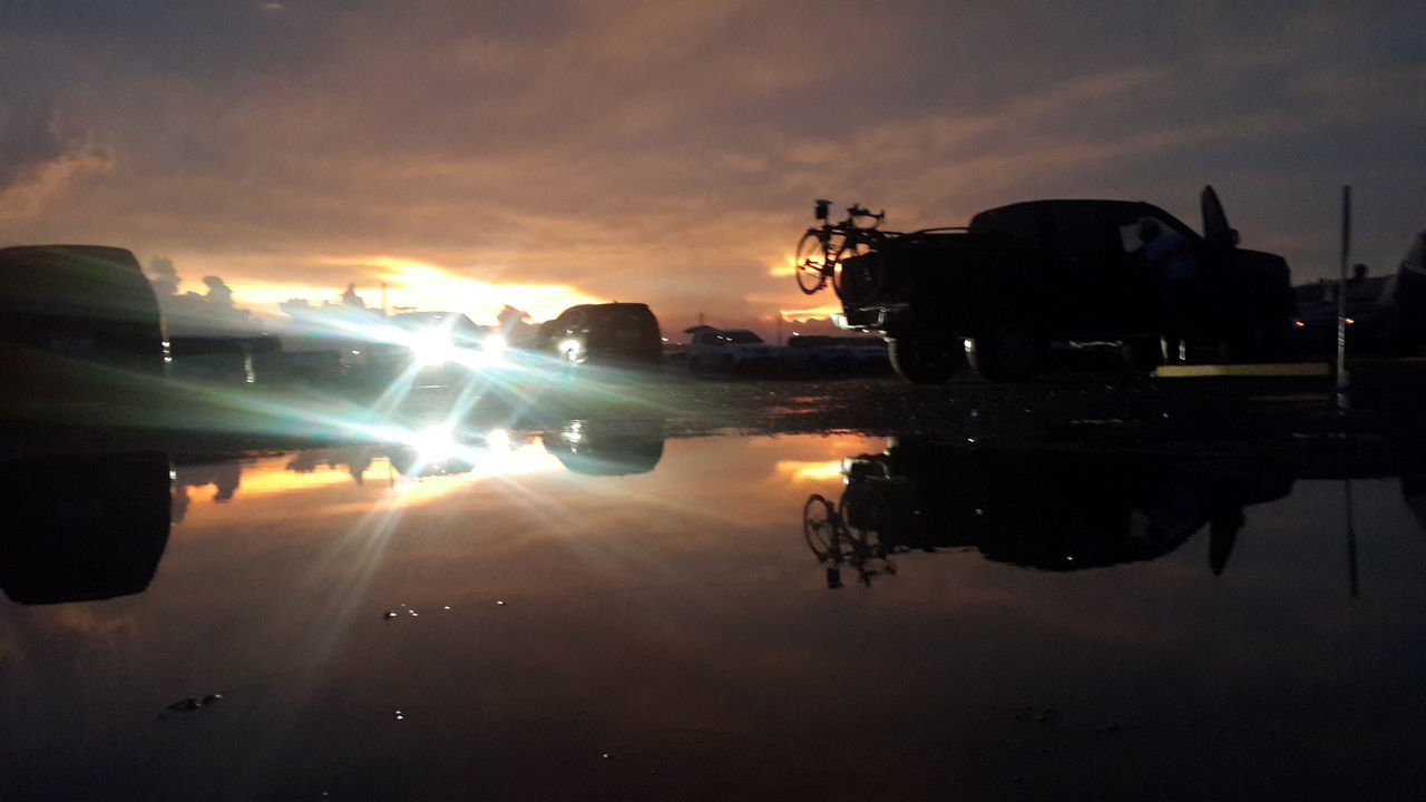 sunset, transportation, sky, mode of transport, land vehicle, silhouette, cloud - sky, car, building exterior, built structure, architecture, dusk, orange color, street, outdoors, travel, water, weather, sun, cloud