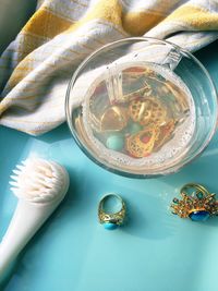 High angle view of jewelries in bowl and brush on table