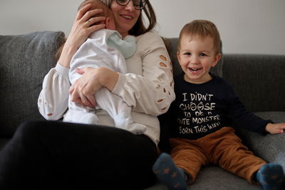 Portrait of happy friends sitting on sofa at home