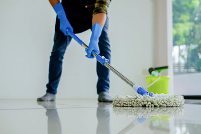 Low section of woman moping floor at home