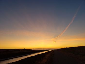 Road amidst silhouette landscape against sky during sunset