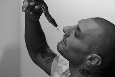 Close-up side view of man holding snake outdoors