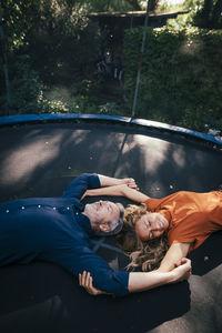 Happy mature couple lying on trampoline in back yard