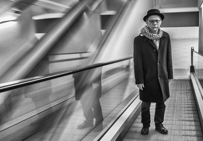 Full length portrait of senior man standing on moving walkway