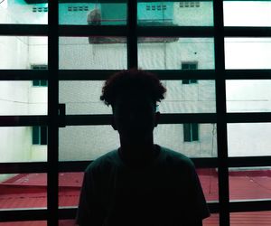 Portrait of young man looking through window