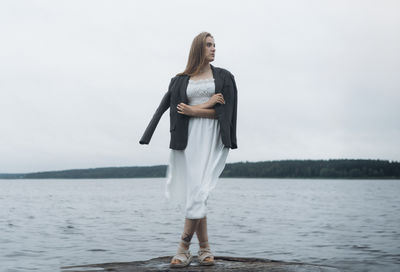 Portrait of young woman standing against lake