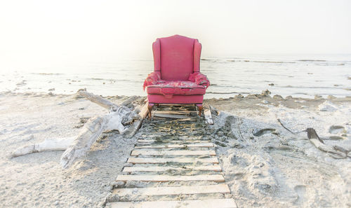 Deck chairs on beach against clear sky