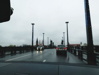 Cars on road against sky seen through car windshield