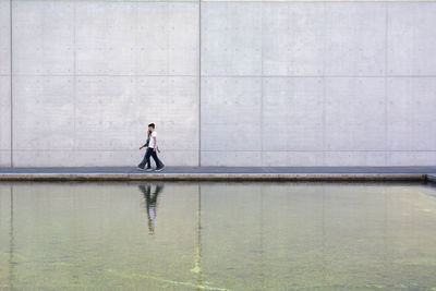 Man and woman walking on sidewalk by river