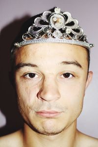 Close-up portrait of man wearing crown by wall