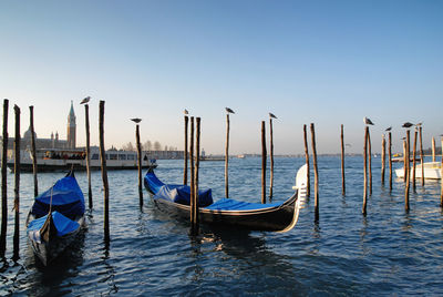 Boats moored in canal against clear blue sky
